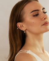 Gesichtsfoto eines Model mit einem Ohr, dass mit vielen Ohr Piercings geschmückt ist.